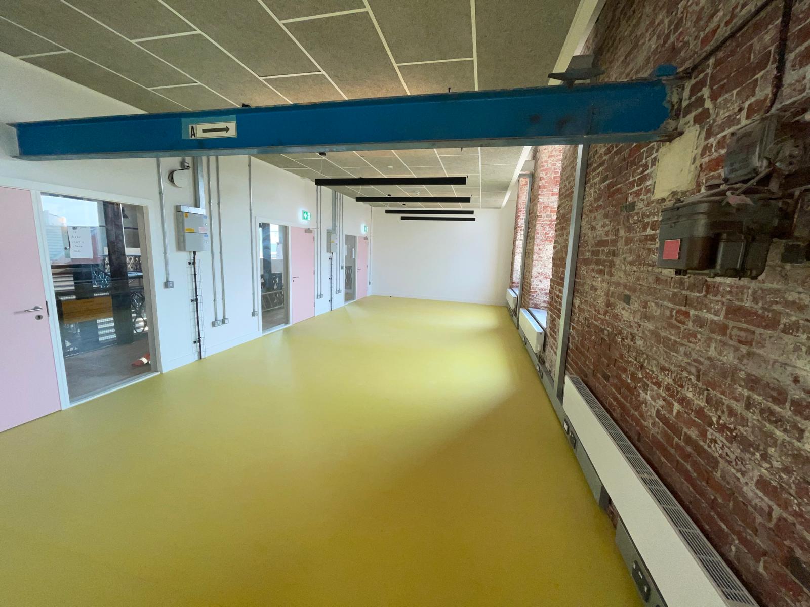 Long open-plan commercial space with yellow-green Forbo Marmoleum flooring