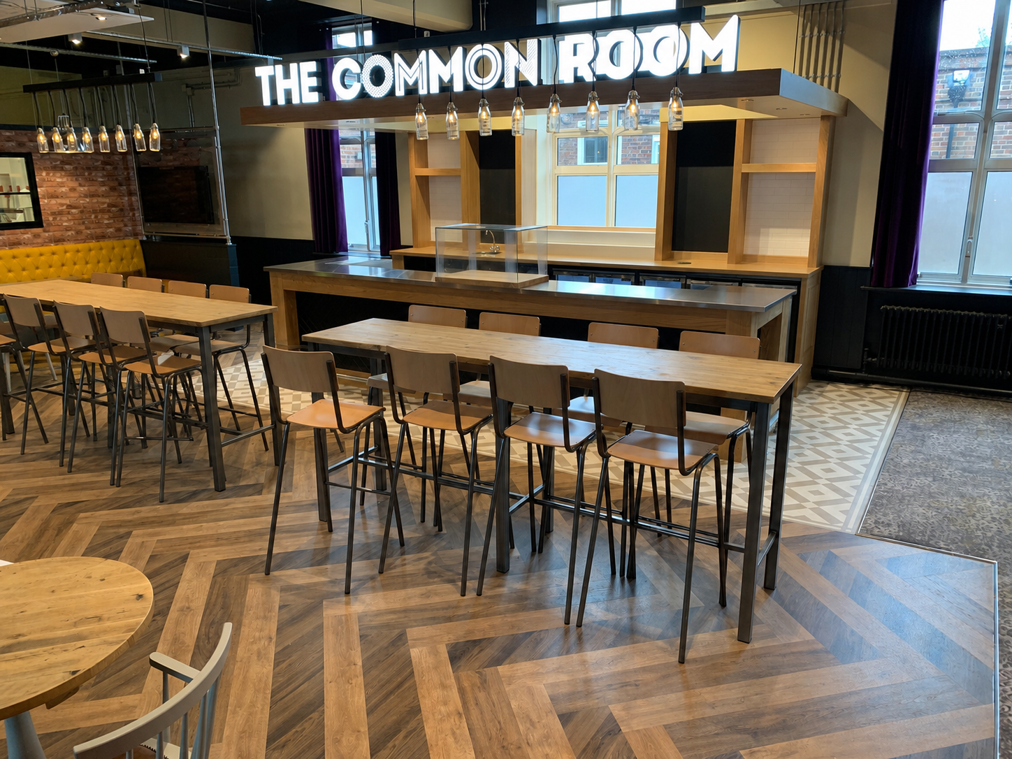Hospitality bar area with herringbone wood-effect LVT flooring and high tables
