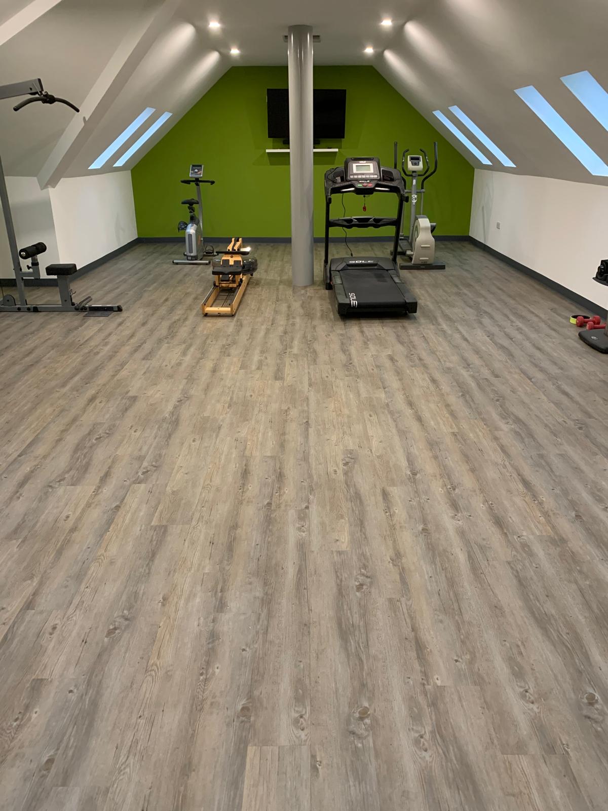 Home gym with grey wood-effect LVT flooring and exercise equipment