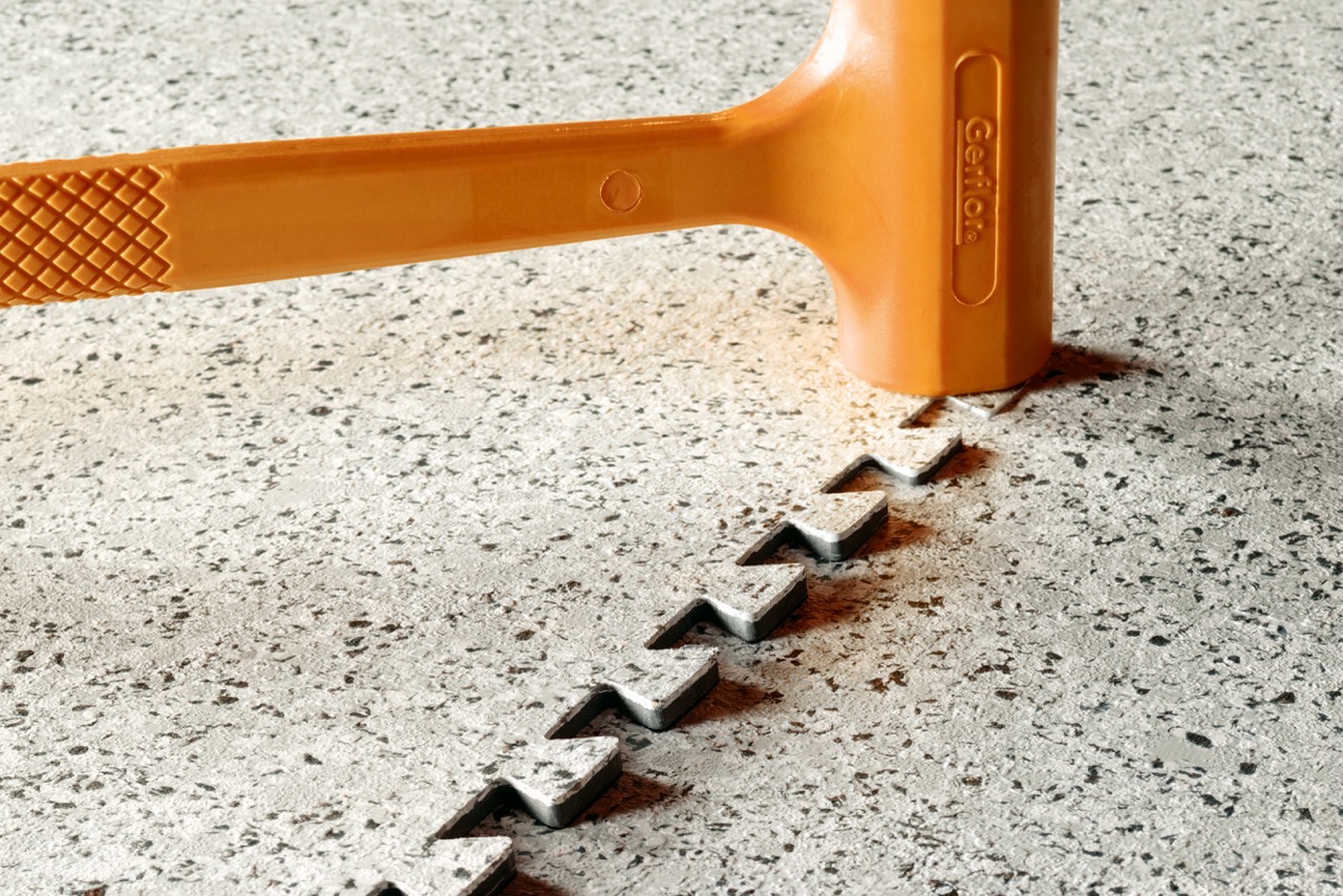 Close-up of orange-speckled interlocking floor tile with mallet