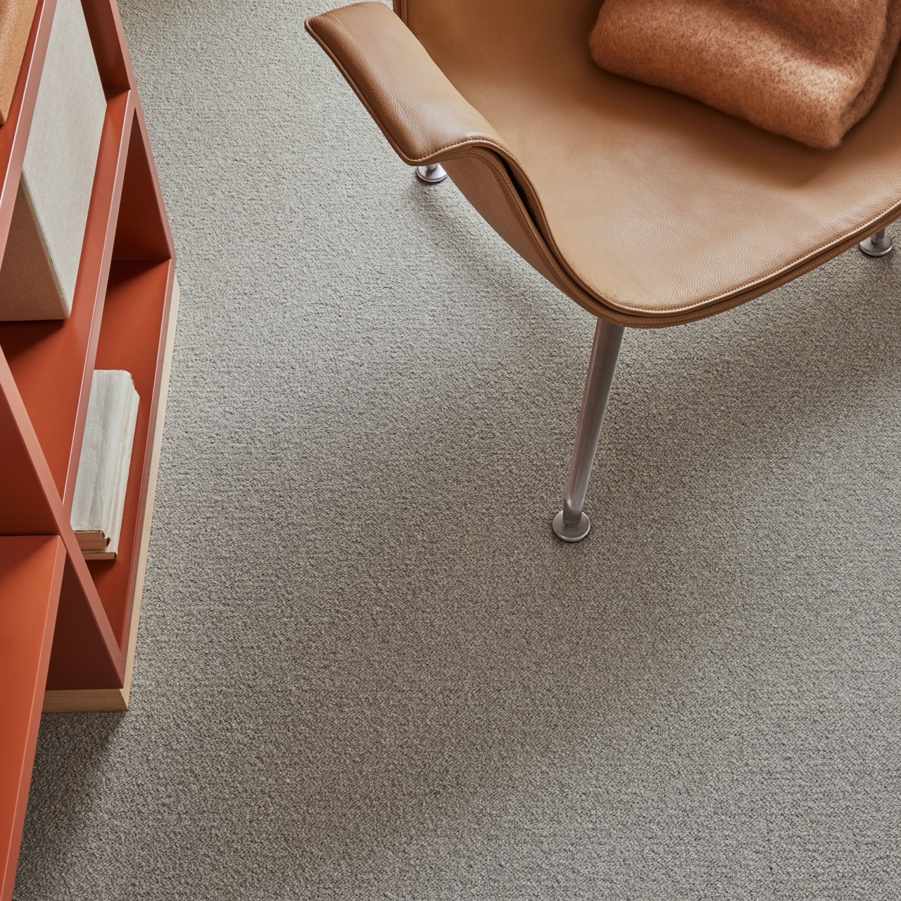 High Resolution-Tessera Chroma 3609 coconut close up Large Close-up of neutral speckled carpet tile with an orange shelving unit and leather chair