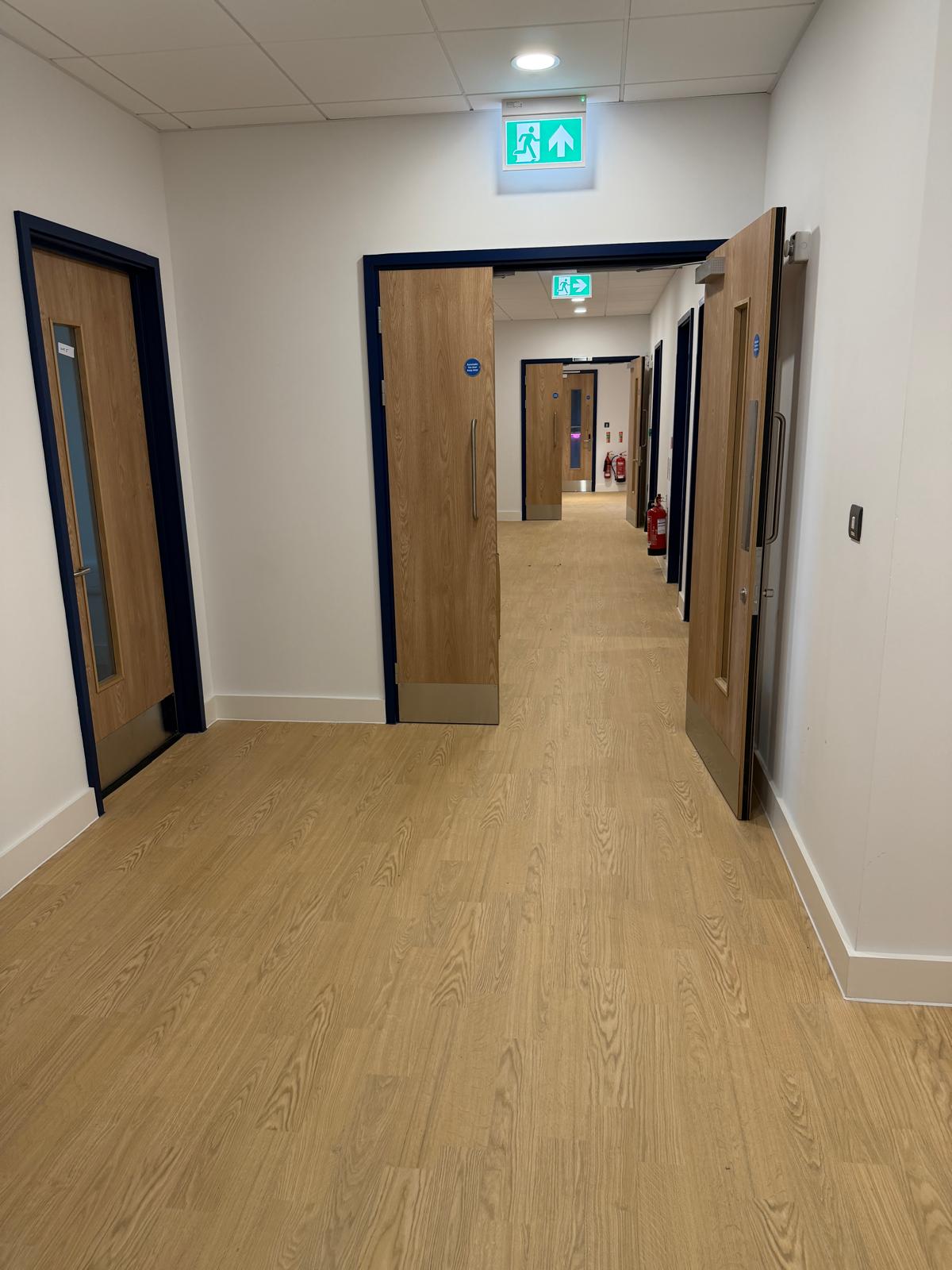 School corridor with oak-effect vinyl flooring and wooden doors