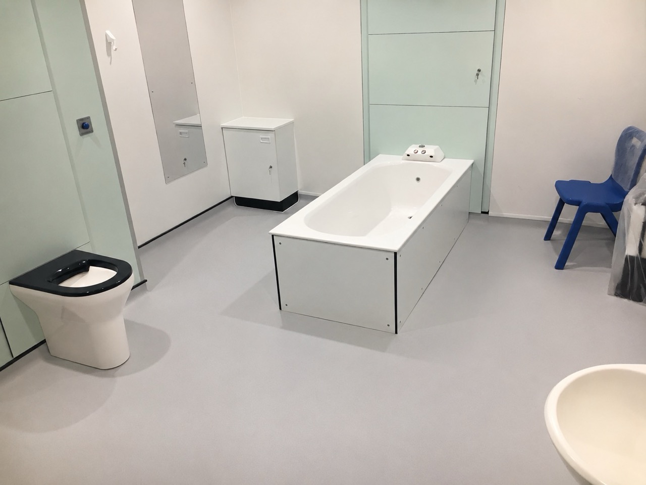 Healthcare bathroom with grey slip-resistant vinyl flooring and accessible bath