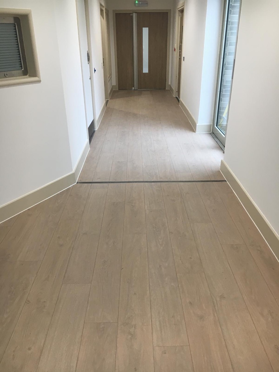 Healthcare corridor with light wood-effect vinyl flooring