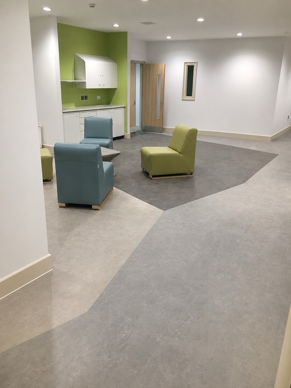 Healthcare lounge area with grey vinyl flooring and curved inset feature design